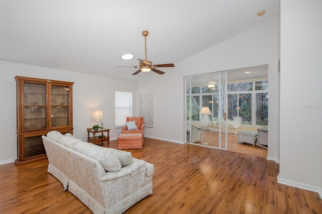 living room with lofted ceiling, ceiling fan, and light wood-type flooring