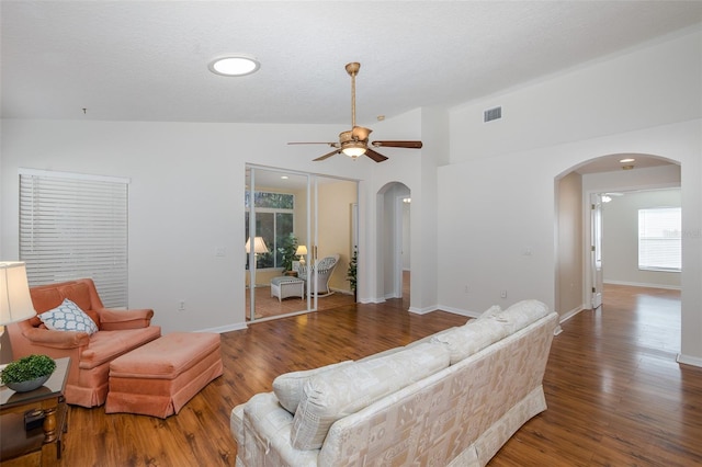 living area with visible vents, a ceiling fan, wood finished floors, arched walkways, and vaulted ceiling