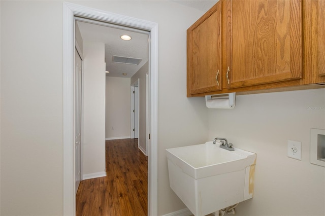 clothes washing area with dark wood-type flooring, cabinets, washer hookup, and sink