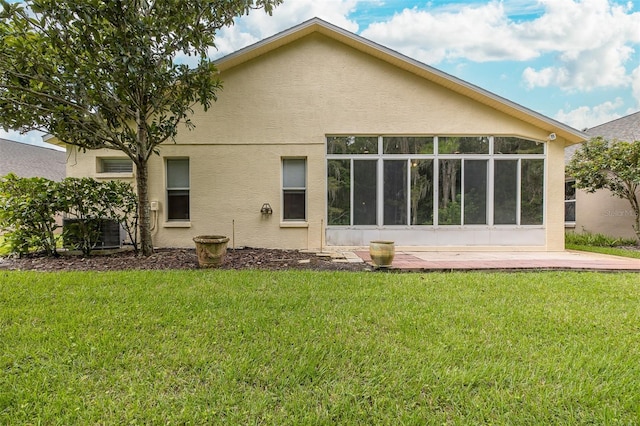 back of house featuring central AC, a yard, a sunroom, and stucco siding