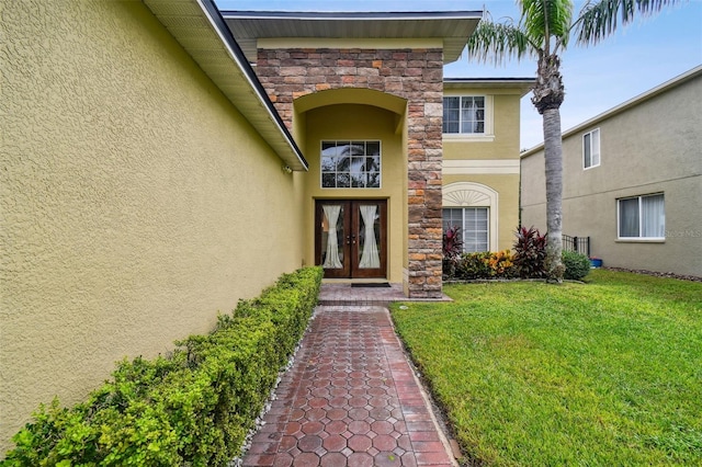 view of exterior entry with a lawn and french doors