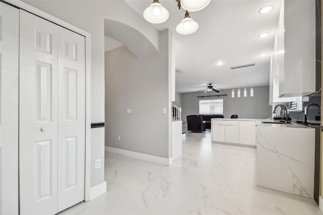 kitchen featuring ceiling fan, white cabinets, and sink