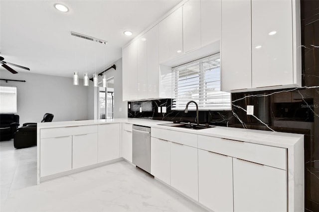 kitchen with stainless steel dishwasher, white cabinets, hanging light fixtures, and sink