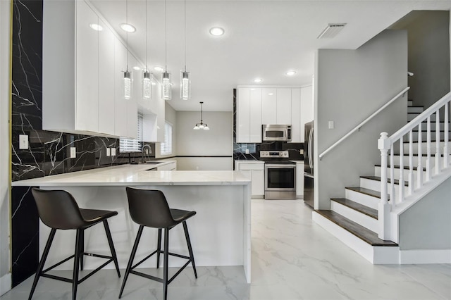 kitchen featuring white cabinetry, stainless steel appliances, kitchen peninsula, and sink