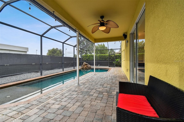 view of pool with glass enclosure, ceiling fan, and a patio