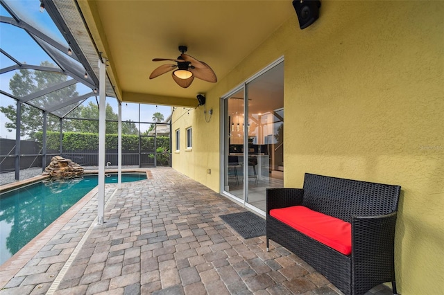 view of swimming pool featuring a patio area, glass enclosure, and ceiling fan