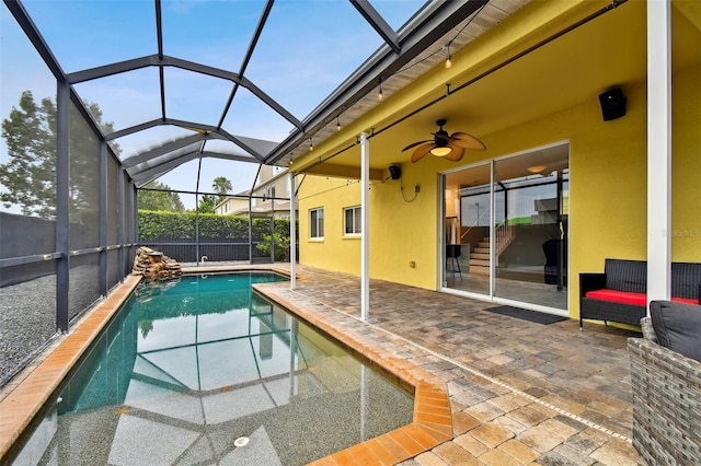 view of swimming pool featuring ceiling fan, glass enclosure, and a patio area