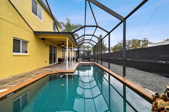 view of swimming pool featuring glass enclosure, a patio area, and ceiling fan