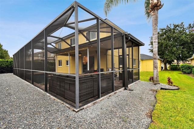 back of property with ceiling fan, a lawn, a patio area, and glass enclosure