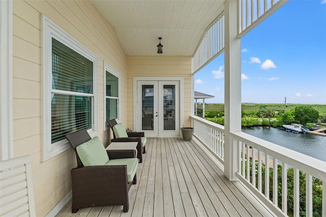 wooden terrace featuring a water view and french doors