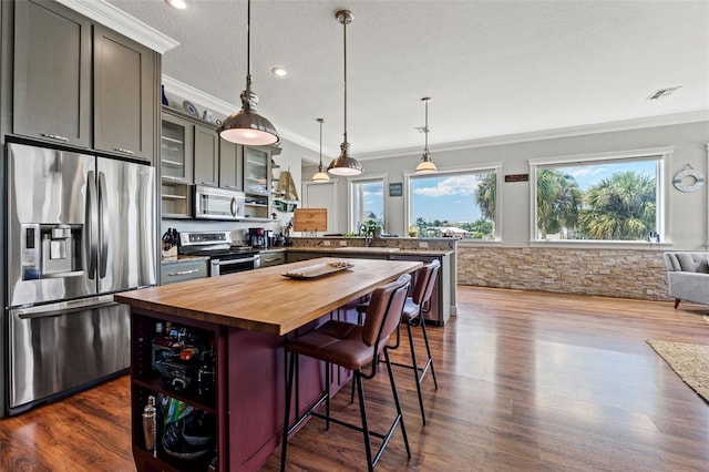 kitchen featuring wooden counters, a kitchen breakfast bar, stainless steel appliances, crown molding, and dark hardwood / wood-style flooring