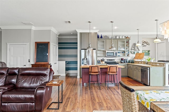 interior space featuring hanging light fixtures, light hardwood / wood-style flooring, gray cabinets, appliances with stainless steel finishes, and a breakfast bar