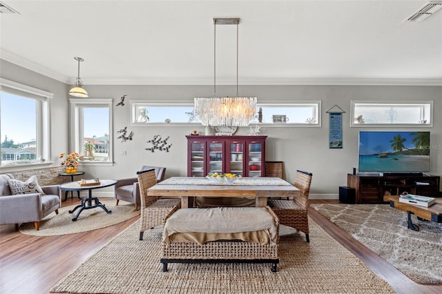 dining area featuring ornamental molding, wood-type flooring, and a chandelier