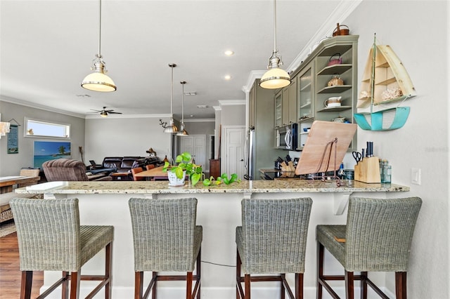 kitchen featuring a breakfast bar, kitchen peninsula, dark hardwood / wood-style flooring, crown molding, and decorative light fixtures