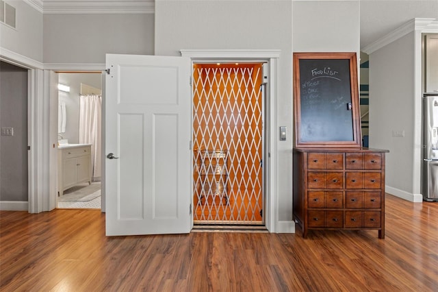 unfurnished bedroom featuring wood-type flooring, ensuite bath, crown molding, and stainless steel fridge