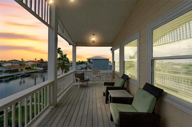 deck at dusk featuring a water view