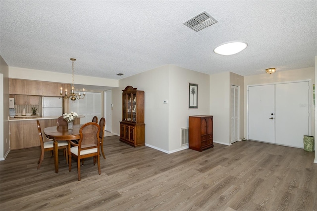 dining space featuring hardwood / wood-style floors, a notable chandelier, and a textured ceiling