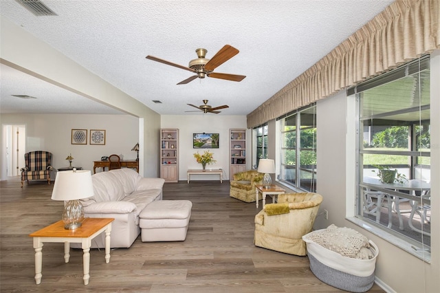 living room featuring a textured ceiling, wood-type flooring, and ceiling fan