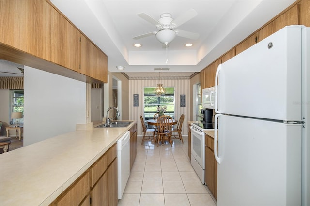 kitchen with a tray ceiling, sink, decorative light fixtures, light tile patterned floors, and white appliances