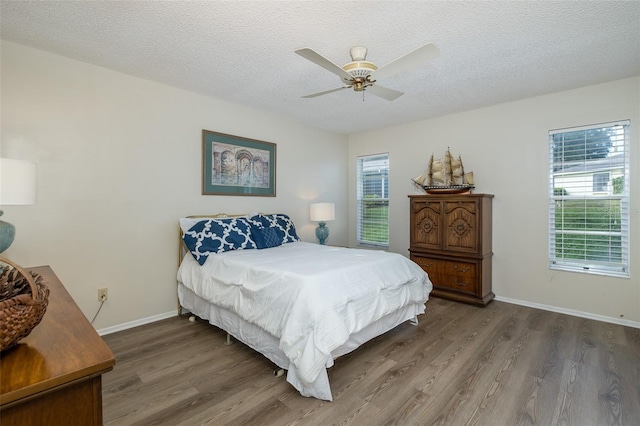 bedroom featuring multiple windows, a textured ceiling, wood-type flooring, and ceiling fan