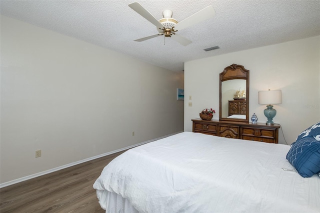 bedroom with ceiling fan, a textured ceiling, and dark hardwood / wood-style flooring