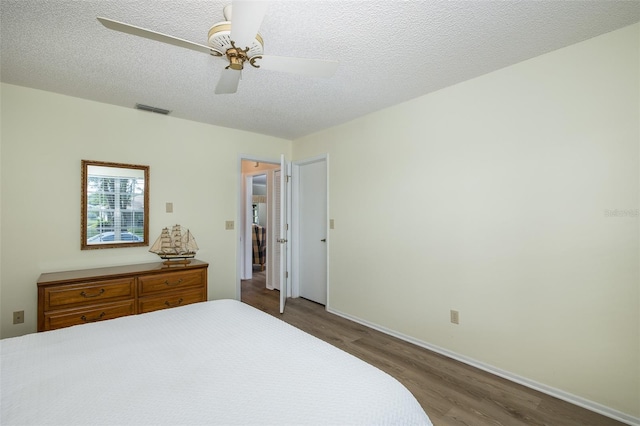 bedroom with a textured ceiling, wood-type flooring, and ceiling fan