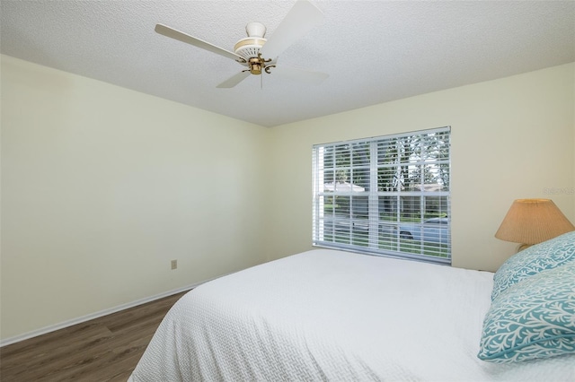 bedroom with dark wood-type flooring, ceiling fan, and a textured ceiling