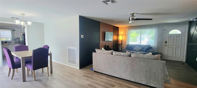 living room featuring ceiling fan with notable chandelier, light hardwood / wood-style floors, and a healthy amount of sunlight