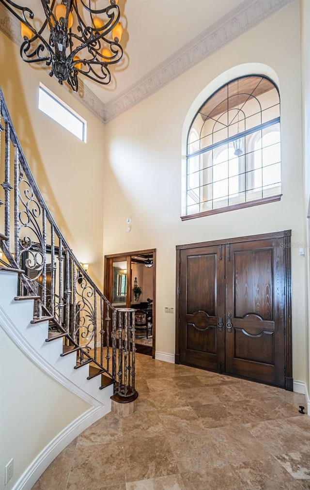 foyer featuring a towering ceiling, ornamental molding, and an inviting chandelier