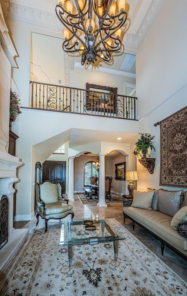 living room featuring ornamental molding, a high ceiling, an inviting chandelier, and ornate columns