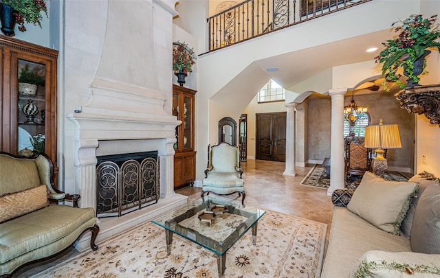 living room with a high ceiling, an inviting chandelier, and decorative columns