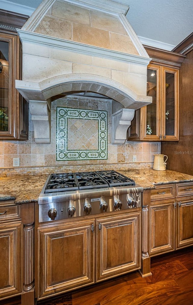 kitchen featuring stainless steel gas stovetop, light stone counters, dark hardwood / wood-style floors, and crown molding