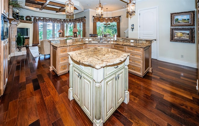 9943 Milano Dr, Trinity, FL 34655 - kitchen with a large island with sink, a sink, dark wood finished floors, cream cabinetry, and an inviting chandelier