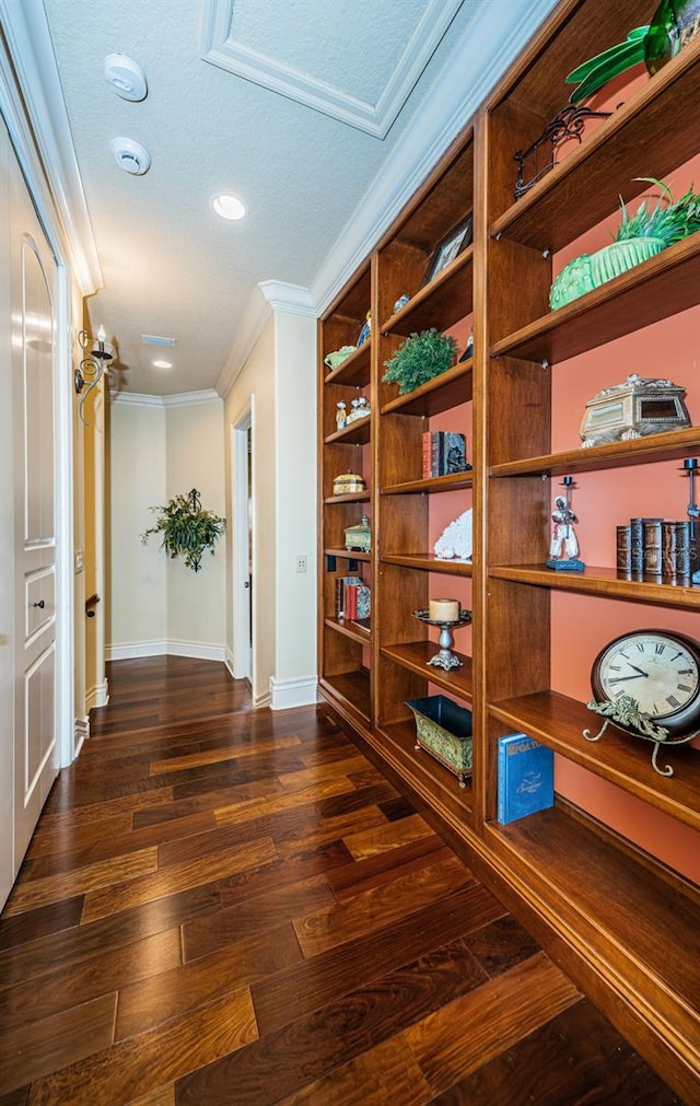 corridor with a textured ceiling, crown molding, and dark hardwood / wood-style floors