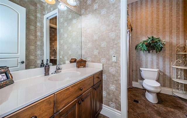9943 Milano Dr, Trinity, FL 34655 - bathroom with toilet, vanity, tile patterned flooring, baseboards, and wallpapered walls