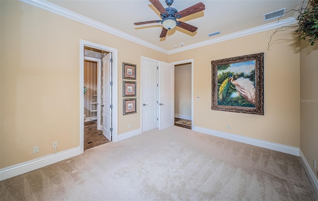 unfurnished bedroom featuring crown molding, light colored carpet, and ceiling fan