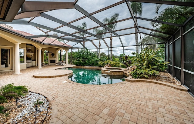 view of swimming pool featuring glass enclosure, an in ground hot tub, and a patio