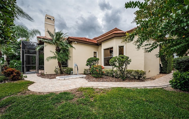 9943 Milano Dr, Trinity, FL 34655 - back of property featuring a tiled roof, glass enclosure, a chimney, stucco siding, and a yard