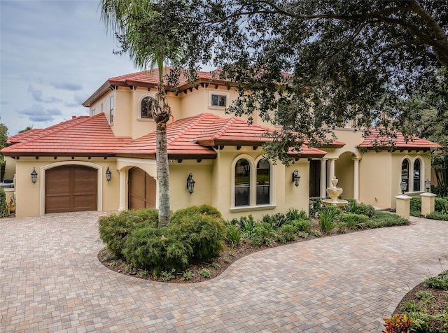 9943 Milano Dr, Trinity, FL 34655 - mediterranean / spanish-style home with stucco siding, a tile roof, a garage, and decorative driveway