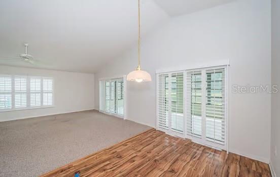 carpeted spare room featuring ceiling fan, plenty of natural light, and high vaulted ceiling