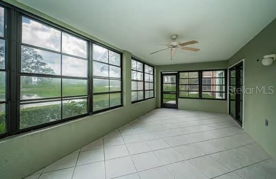 sunroom featuring ceiling fan, a healthy amount of sunlight, and a water view