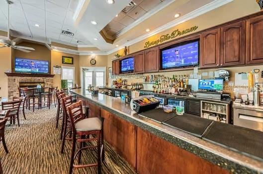 bar featuring crown molding and a fireplace