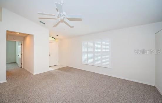 unfurnished room featuring ceiling fan, vaulted ceiling, and light carpet