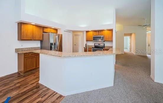 kitchen featuring light stone counters, sink, stainless steel appliances, and kitchen peninsula