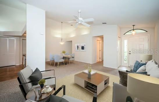 carpeted living room with high vaulted ceiling and ceiling fan