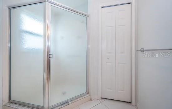 bathroom with tile patterned flooring and a shower with shower door