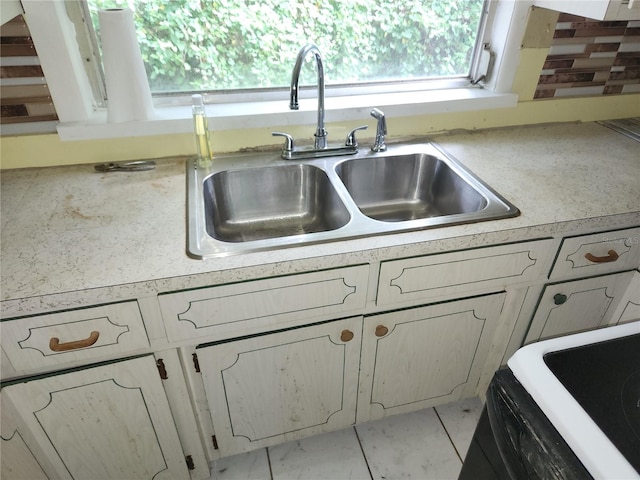 kitchen with a healthy amount of sunlight, backsplash, sink, and light tile patterned floors