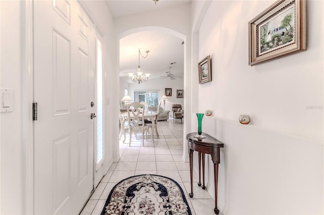 corridor featuring lofted ceiling, a chandelier, and light tile patterned floors