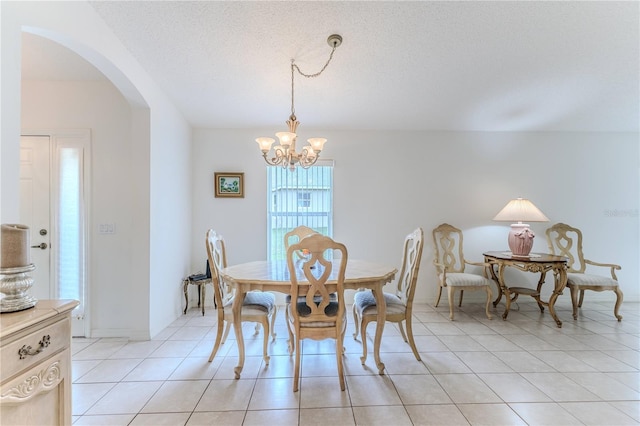 dining space with a textured ceiling, light tile patterned flooring, and a notable chandelier