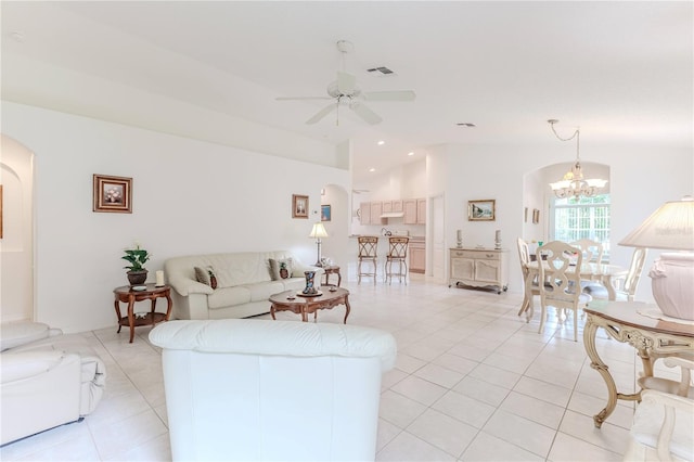 living room with ceiling fan with notable chandelier, light tile patterned floors, and vaulted ceiling